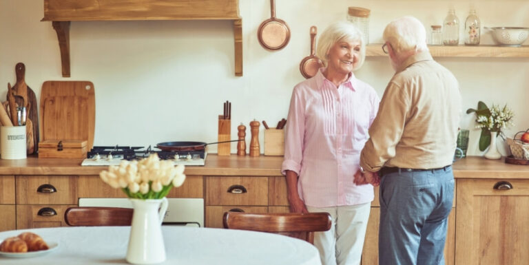 Elderly Couple Holding Hands in Their Cozy Apartment Kitchen at Assisted Living Facility